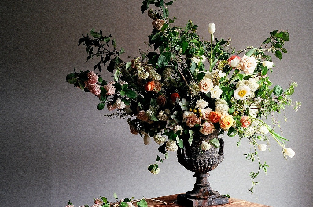 rustic metal urn with large billowing arrangement of peach roses and greenery