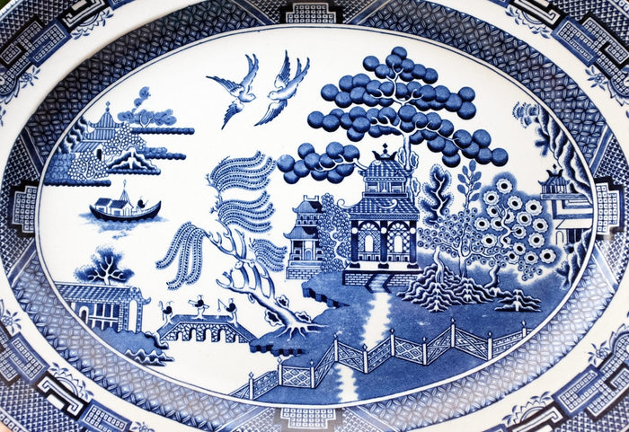Closeup of blue willow platter depicting chinoiserie pastoral scene