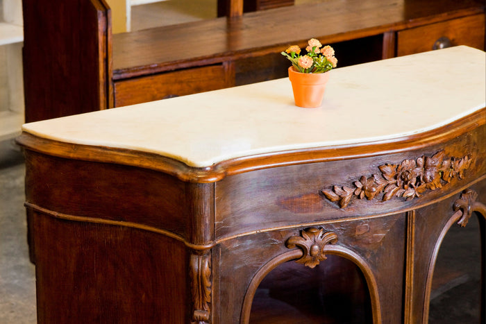 English country sitting room with red and pale blue furniture and accents, yellow flowers on the table in the center, and floral motifi curtains