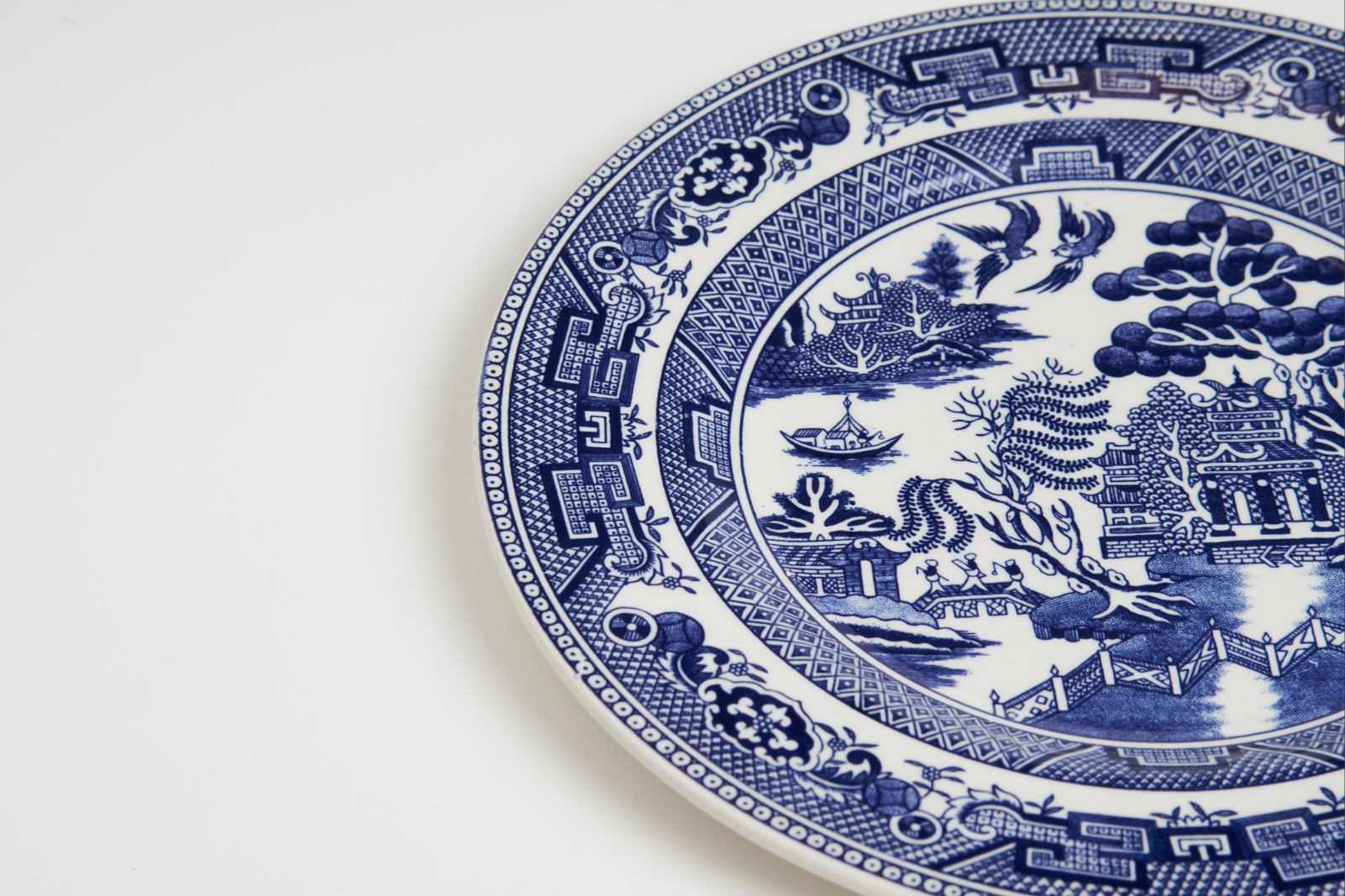 Closeup of blue willow platter depicting chinoiserie pastoral scene