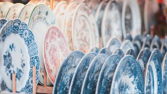 Close up of blue and white transferware platter depicting chinoiserie scene and classical botanical motif around the border