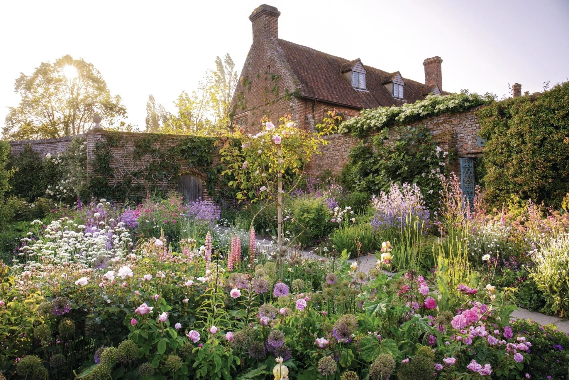 Flower borders at Sissinghurst Castle Garden layered with abundant blooms of pink, lavender, and  white