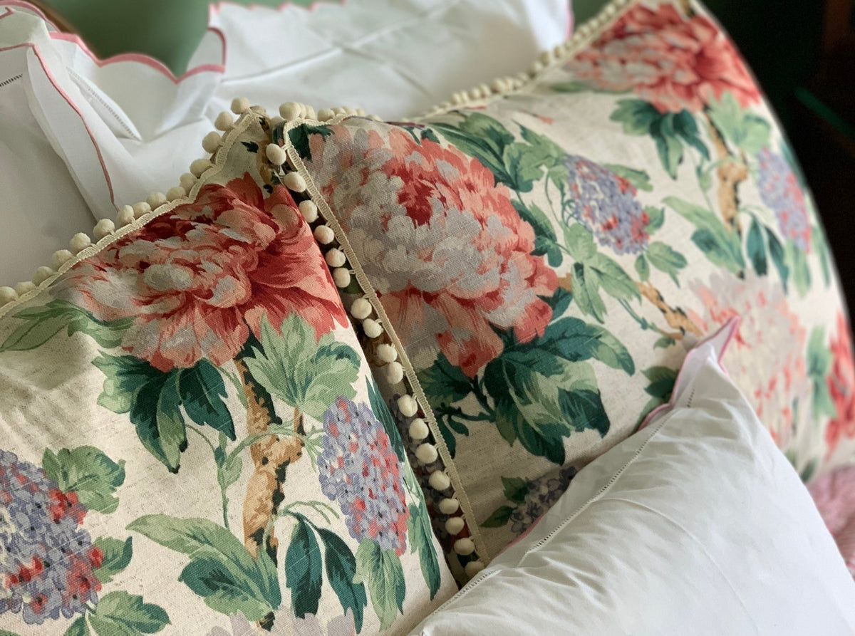 Vintage floral pillow covers with pom-pom trim, upholstered in a 19th-century–style British linen featuring peonies, hydrangeas, and green foliage on a natural ground.