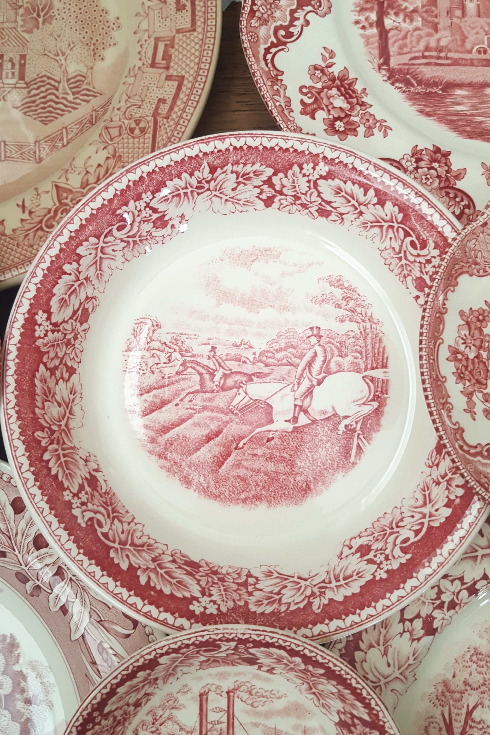 Assorted red Staffordshire transferware plates with pastoral scenes and oak-leaf borders.
